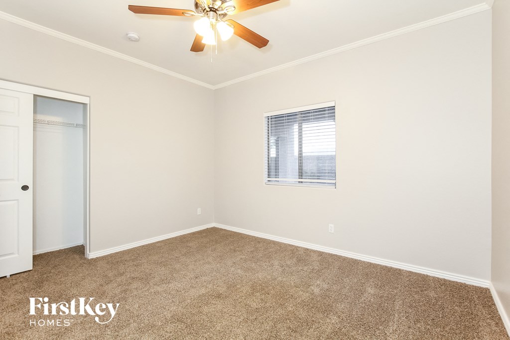 a room with carpet and a ceiling fan and a closet