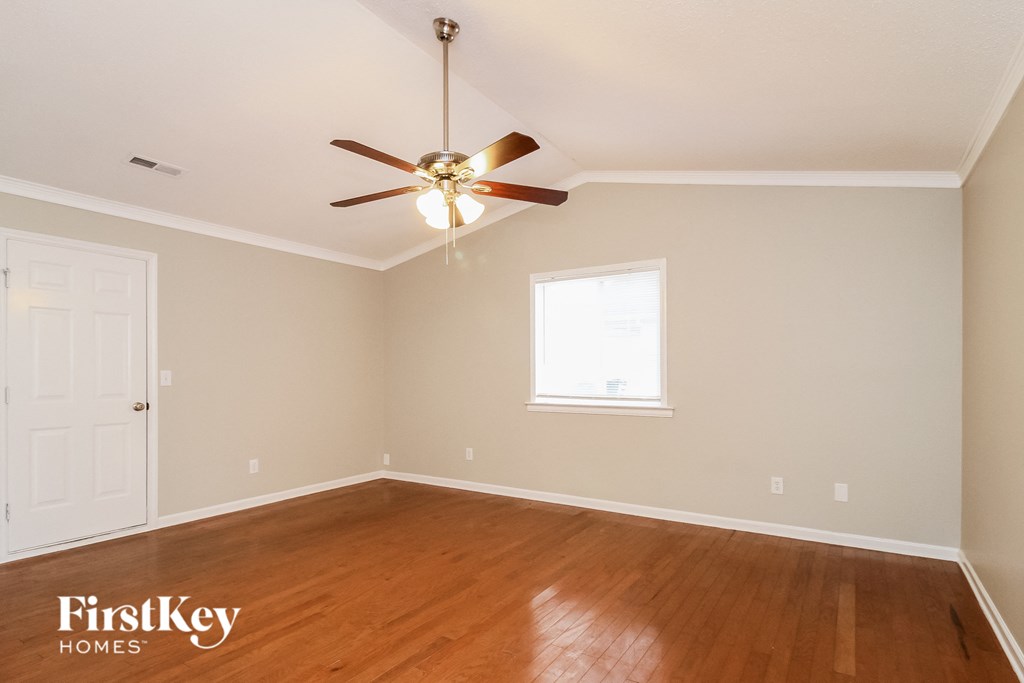 A room with a ceiling fan and wooden floors.