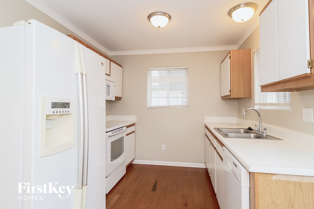 A kitchen with white appliances and wooden cabinets.