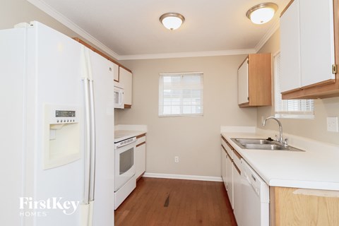 A kitchen with white appliances and wooden cabinets.