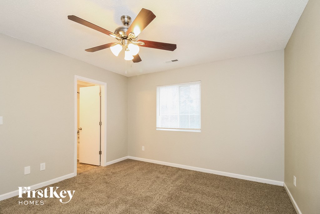 A room with a carpet floor and a ceiling fan.