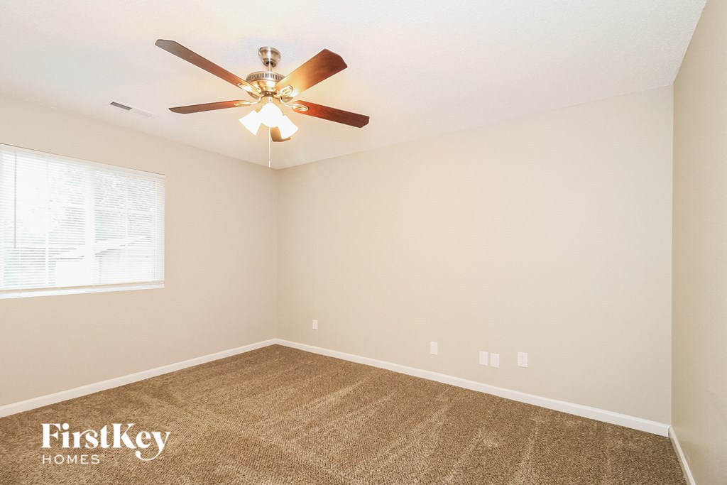 A room with a ceiling fan and a window with blinds.