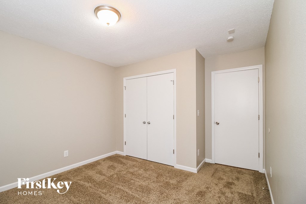 A room with two white doors and a carpeted floor.