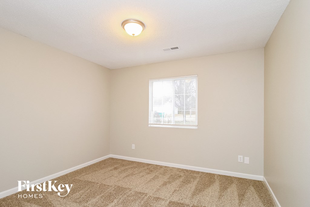 A room with a carpeted floor and a window letting in natural light.
