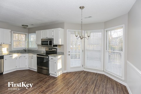 A kitchen with white cabinets and a wooden floor.