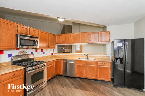 A kitchen with wooden cabinets and a black refrigerator.