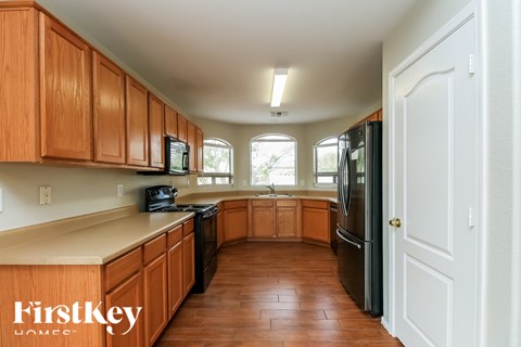 A kitchen with wooden cabinets and a black refrigerator.