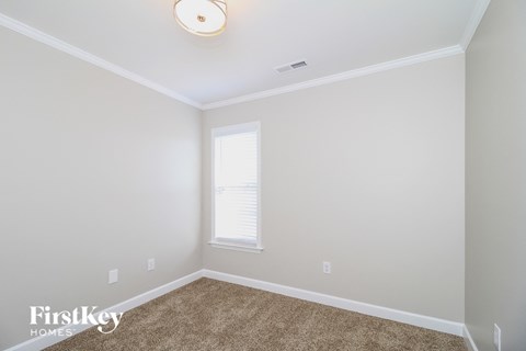 a bedroom with white walls and carpet and a window