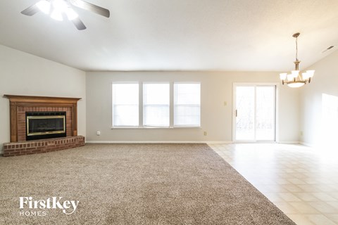 A spacious room with a fireplace and a rug on the floor.