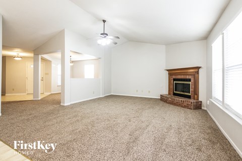A spacious living room with a fireplace and carpeted floor.