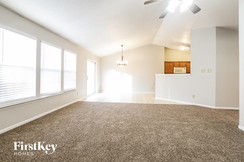 A spacious room with a carpeted floor and a ceiling fan.