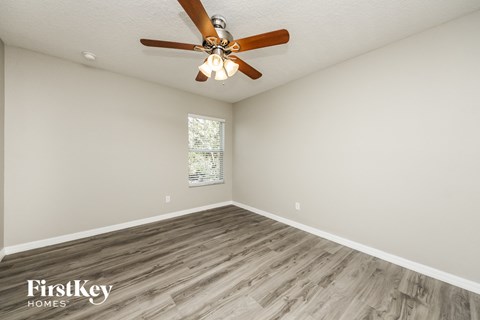 the spacious living room with wood flooring and a ceiling fan