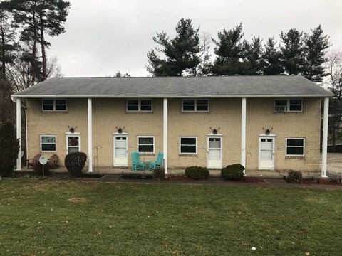 A small building with a porch and a green lawn in front.