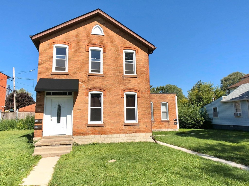 A red brick house with a white door and windows.