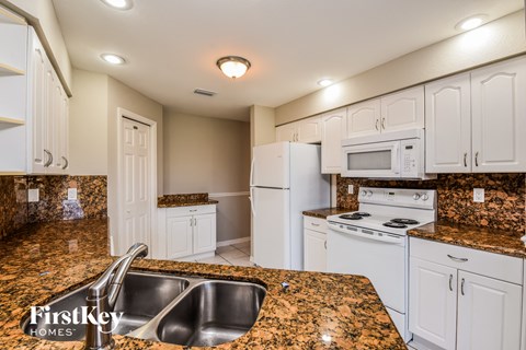 a kitchen with white appliances and granite counter tops