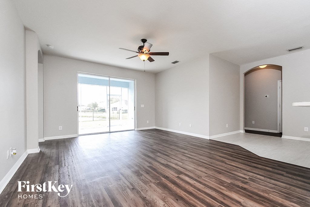 an empty living room with wood flooring and a ceiling fan