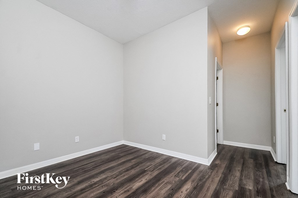 the spacious living room with wood flooring and white walls