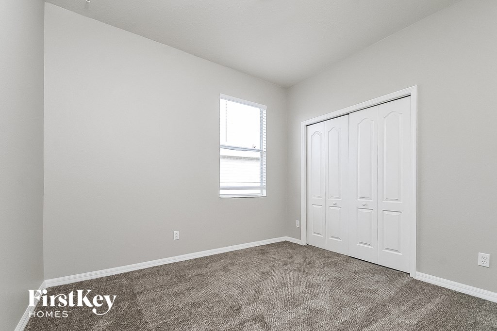 a bedroom with carpet and a white door and window