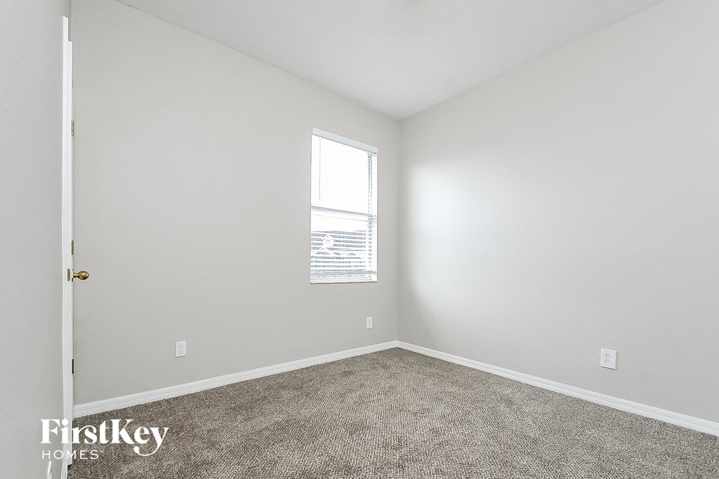 a bedroom with white walls and carpet and a window