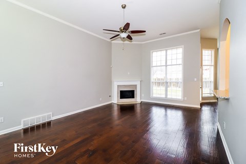 A spacious living room with a fireplace and a ceiling fan.