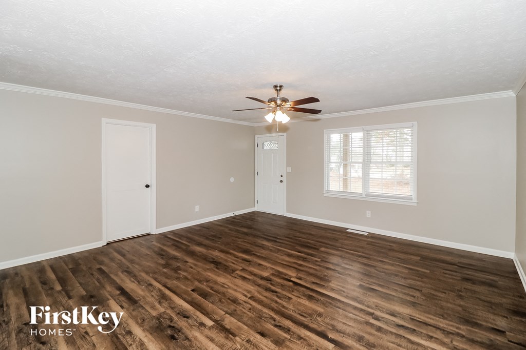 the living room of an empty house with a ceiling fan