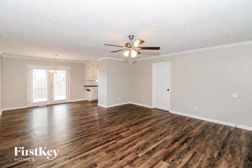 an empty living room with a ceiling fan and a kitchen