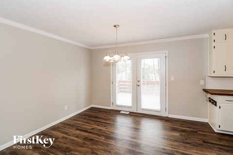 the kitchen and dining room of a home with wood floors and white cabinets
