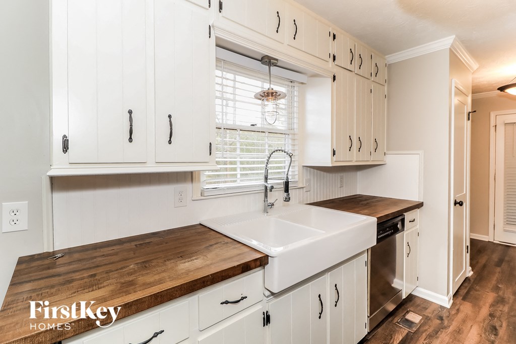 a white kitchen with wooden counter tops and a sink