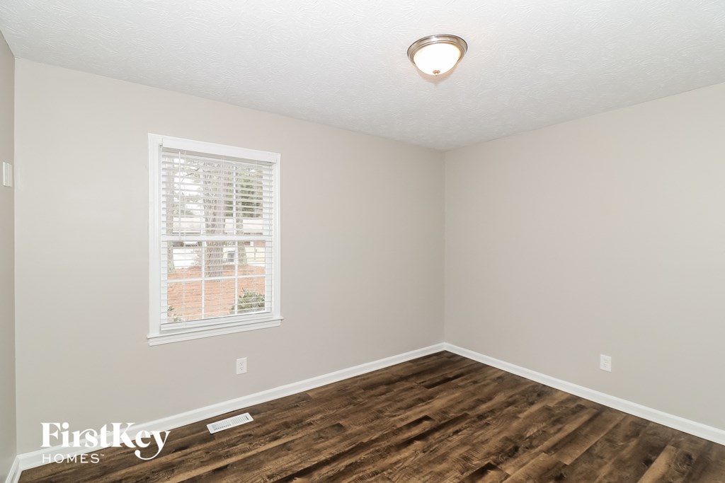 a bedroom with wood flooring and a window