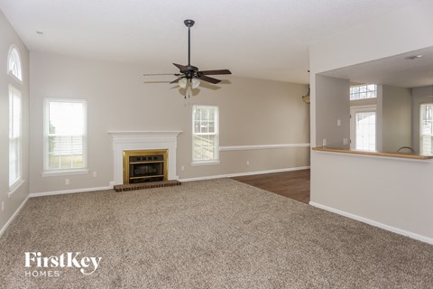 A spacious room with a fireplace and a ceiling fan.