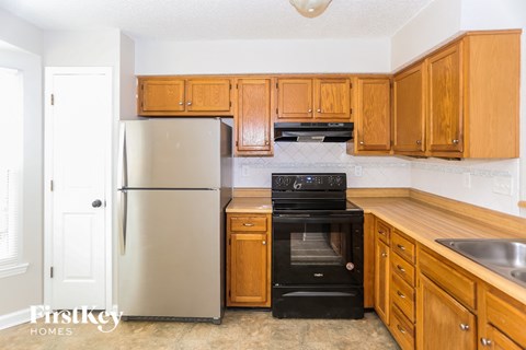 A kitchen with wooden cabinets and a stainless steel refrigerator.