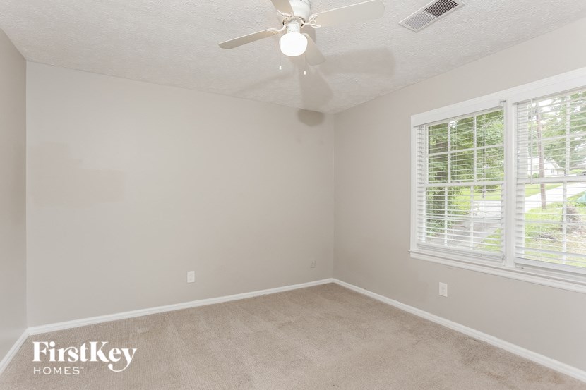 a bedroom with two windows and a ceiling fan