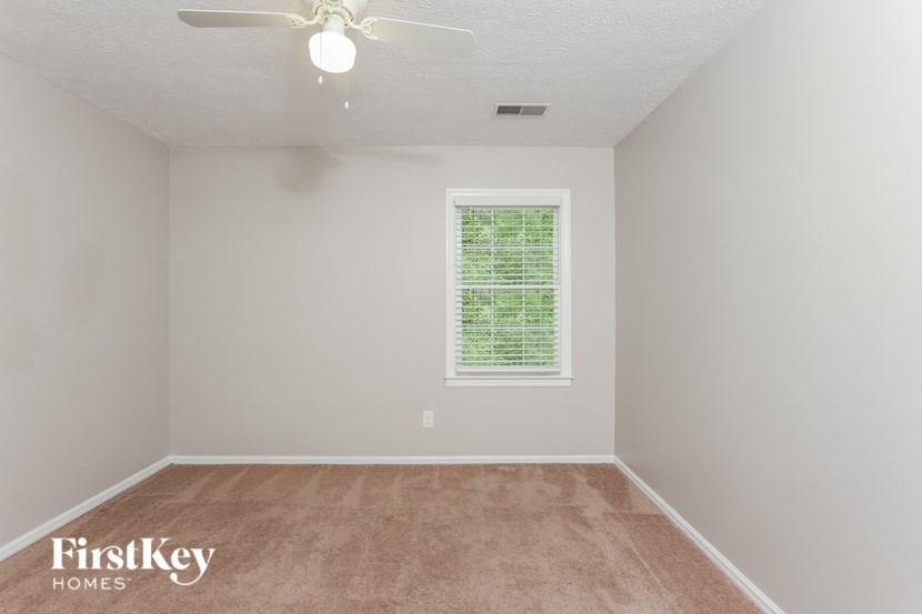 a empty room with a ceiling fan and a window