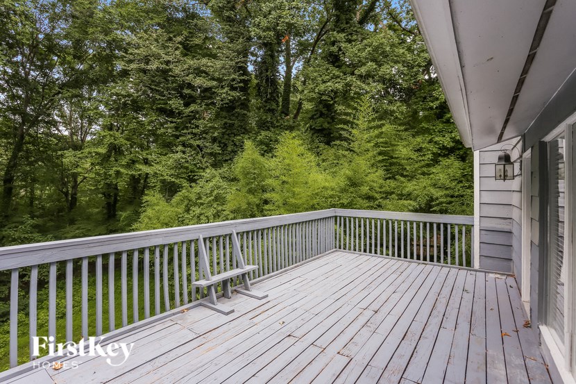 a chair on the deck of a house overlooking the woods