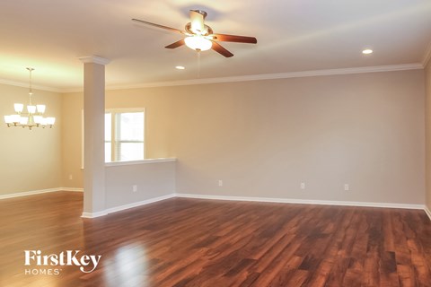 an empty living room with a ceiling fan and a window