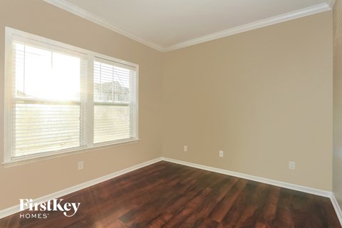 an empty room with wooden floors and two windows