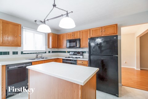 a kitchen with a white counter top and a black refrigerator
