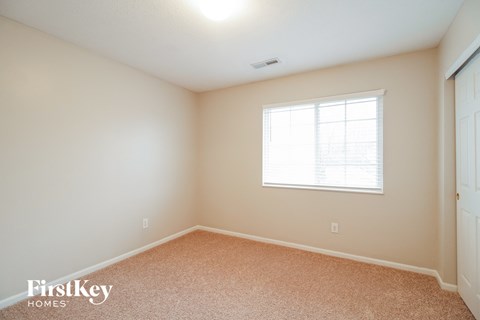 a bedroom with carpet and a window and a door