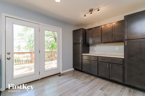 A kitchen with dark brown cabinets and a white door leading to a balcony.