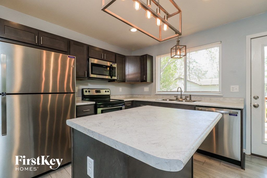 A modern kitchen with a stainless steel refrigerator and a marble countertop.