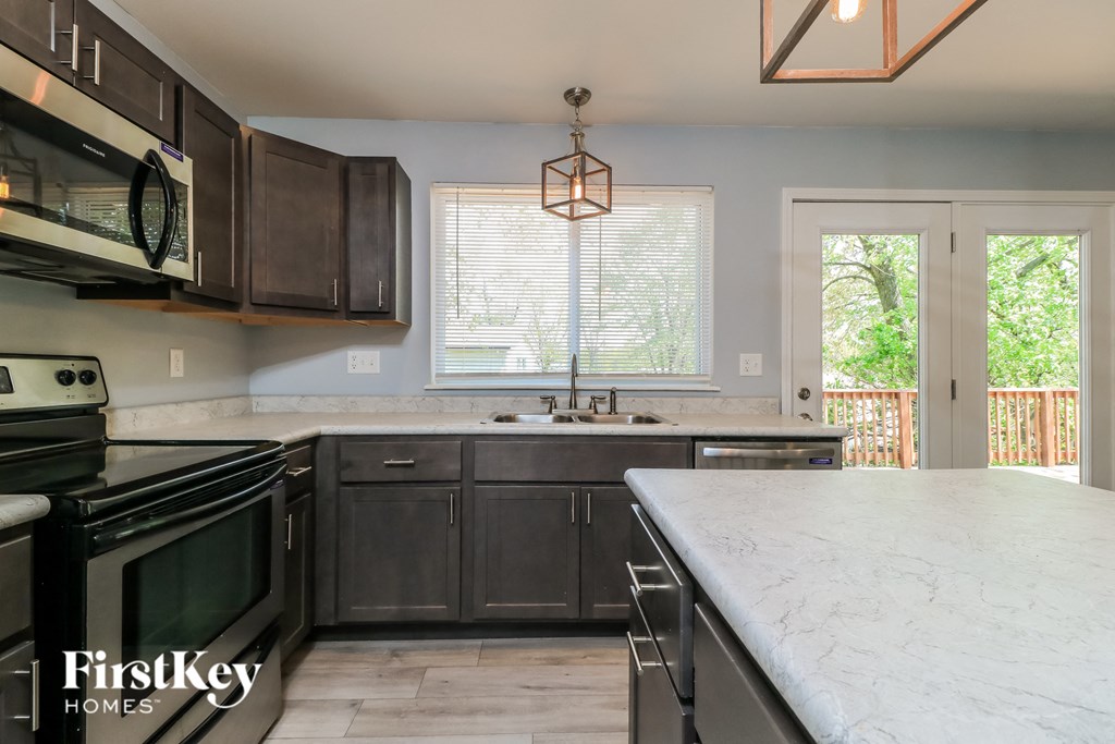 A kitchen with a marble counter top and a large window.