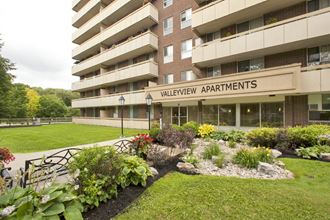 Exterior entrance of Valleyview Apartments with wooden benches and healthy flowerbeds