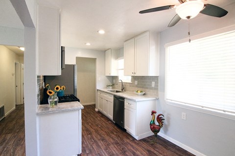 a kitchen with white cabinets and a large window