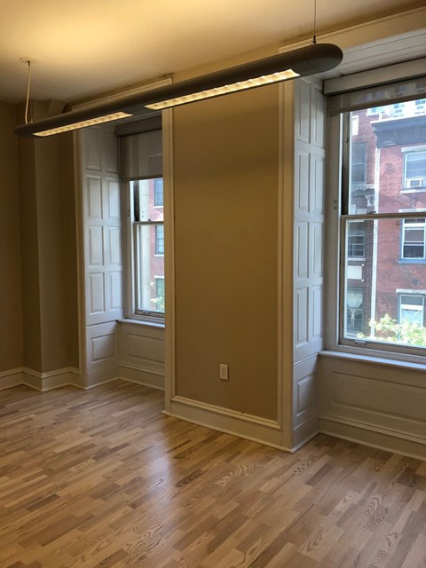 a living room with two windows and a wooden floor
