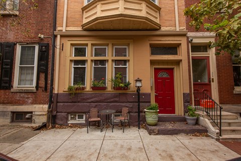 the front of a house with a patio and a red door
