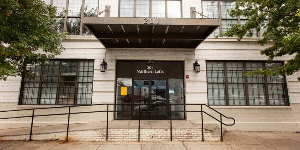 the front of a building with a glass door and stairs