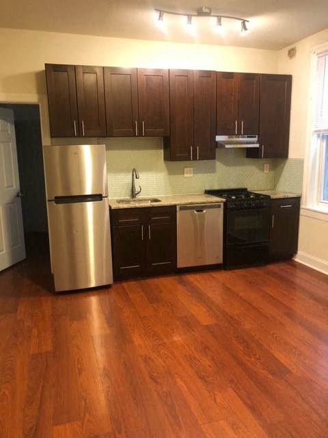 a kitchen with stainless steel appliances and wooden floors