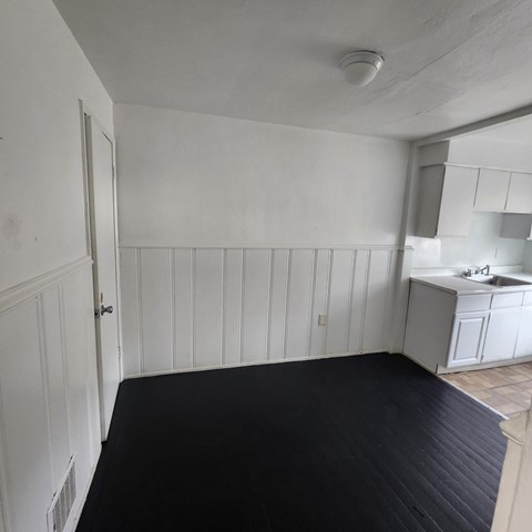 A kitchen with white cabinets and a black floor.