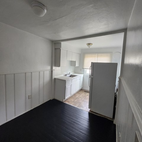 A kitchen with white cabinets and a black floor.
