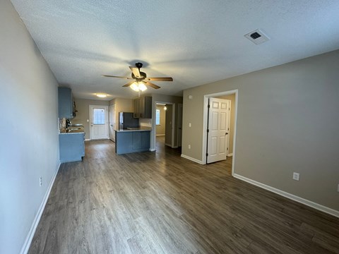 A spacious room with a ceiling fan and lighting fixture.